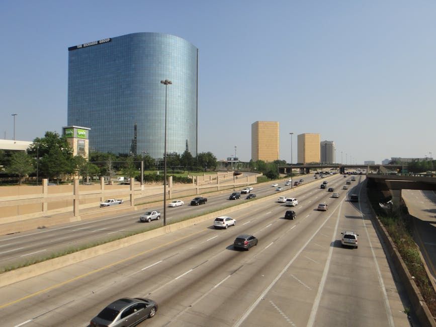 A bustling highway with modern skyscrapers under a clear sky, capturing urban life.