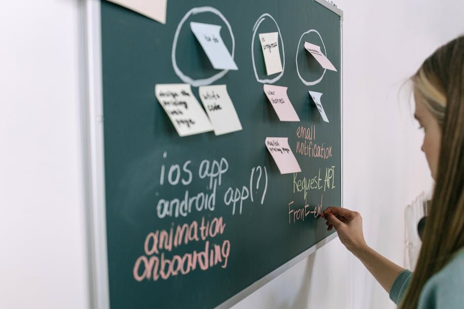 Woman writing on chalkboard during a brainstorming session in an office setting.