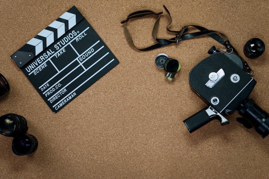 Flat lay of vintage cinema equipment with a film slate and camera on a cork board background.